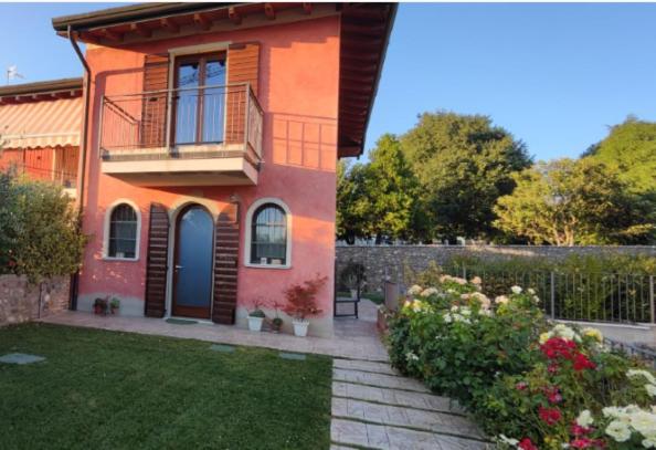 a red house with a balcony and a yard at La Mocina casa vacanze in Castellaro