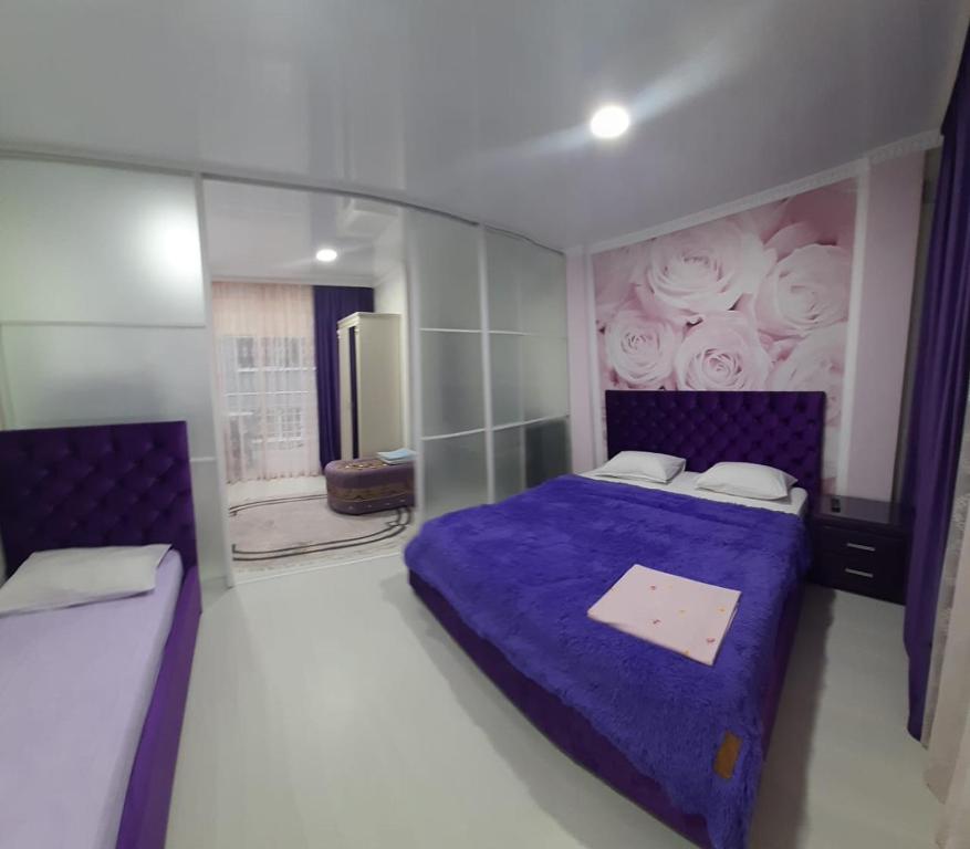 加格拉的住宿－Гостевой дом ЛОНТАНА，卧室配有一张紫色床,墙上涂有玫瑰花