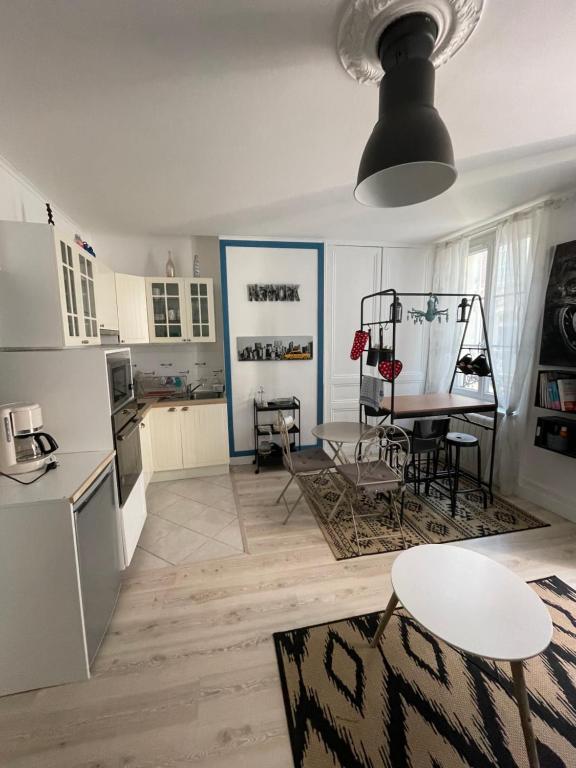 a kitchen with white cabinets and a table and a table and chairs at Le Bleu in Trouville-sur-Mer