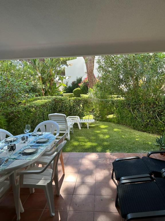 een tafel en stoelen op een patio met een tuin bij Solar dos Pinheiros 105 in Vilamoura