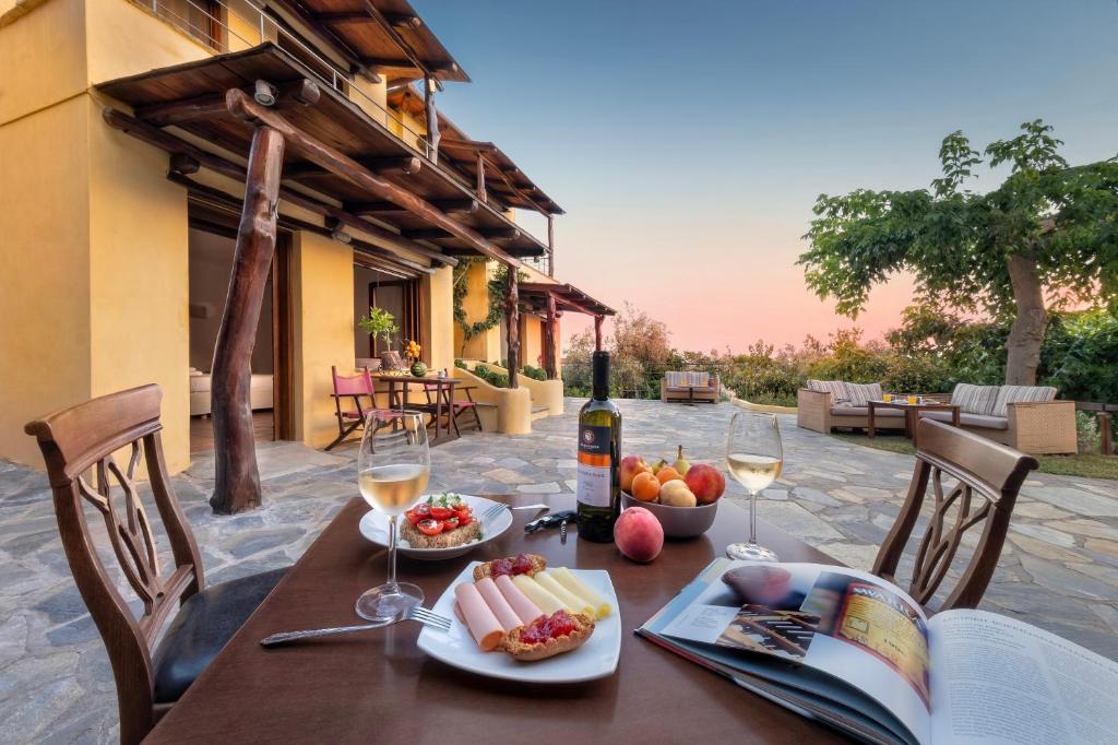 a table with a bottle of wine and a plate of food at Alkifron Hotel in Kala Nera