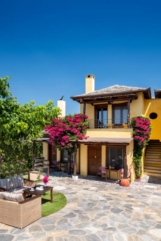 a house with pink flowers and a patio at Alkifron Hotel in Kala Nera