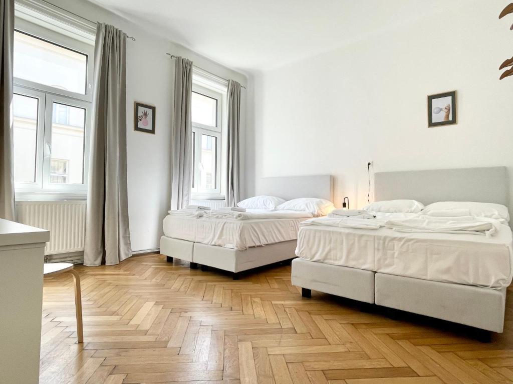 two beds in a white room with two windows at Luxury Apartment at famous Vienna Kutschkermarkt in Vienna