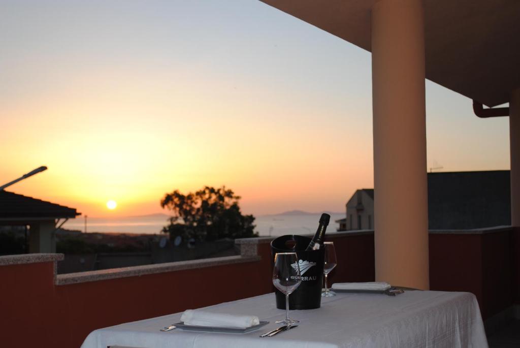 una mesa con una copa de vino y una puesta de sol en La Terrazza sul Golfo, en Sennori