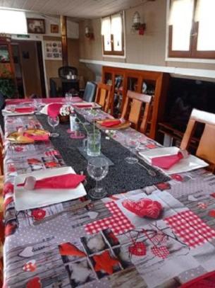 a long table with red and white plates and wine glasses at Bateau Mariance in Ginestas