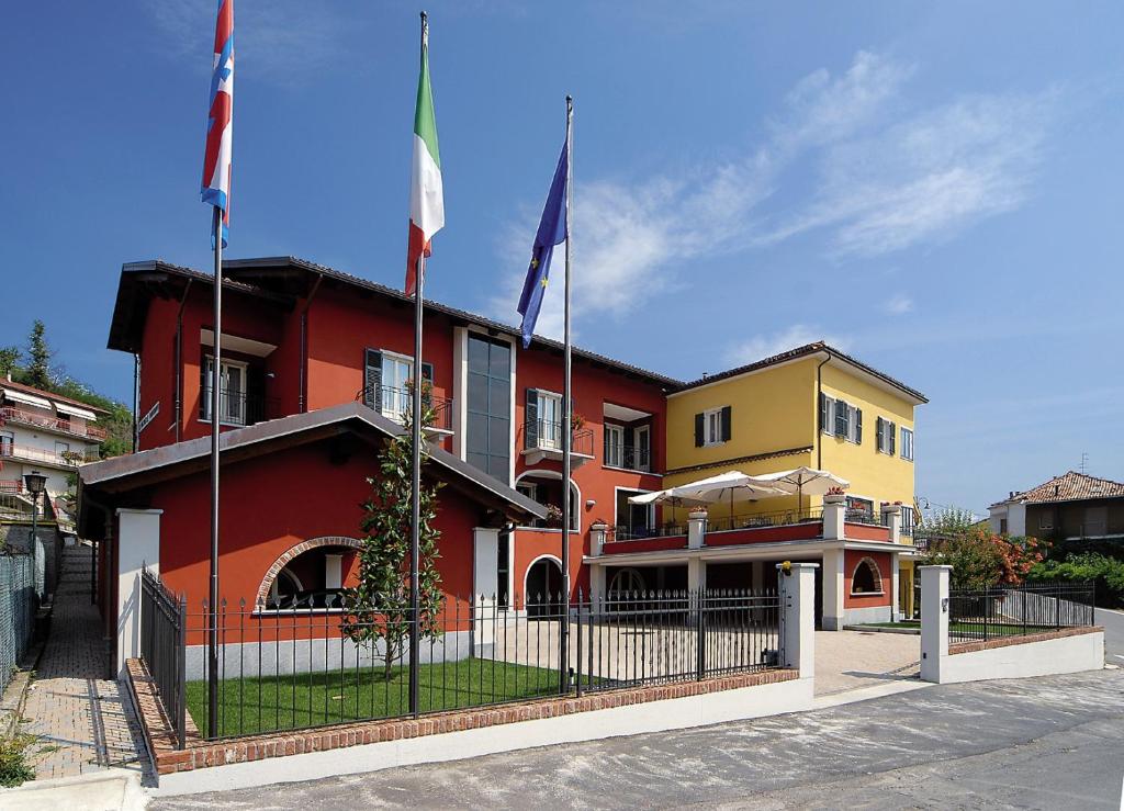 a red building with three flags in front of it at Hotel Ristorante del Peso in San Michele Mondovì