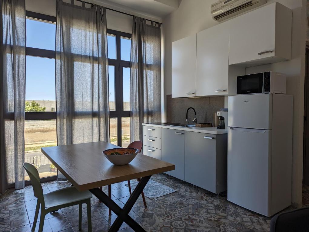 una cucina con tavolo, frigorifero e finestra di Monolocale Viale Arbatax a Tortolì