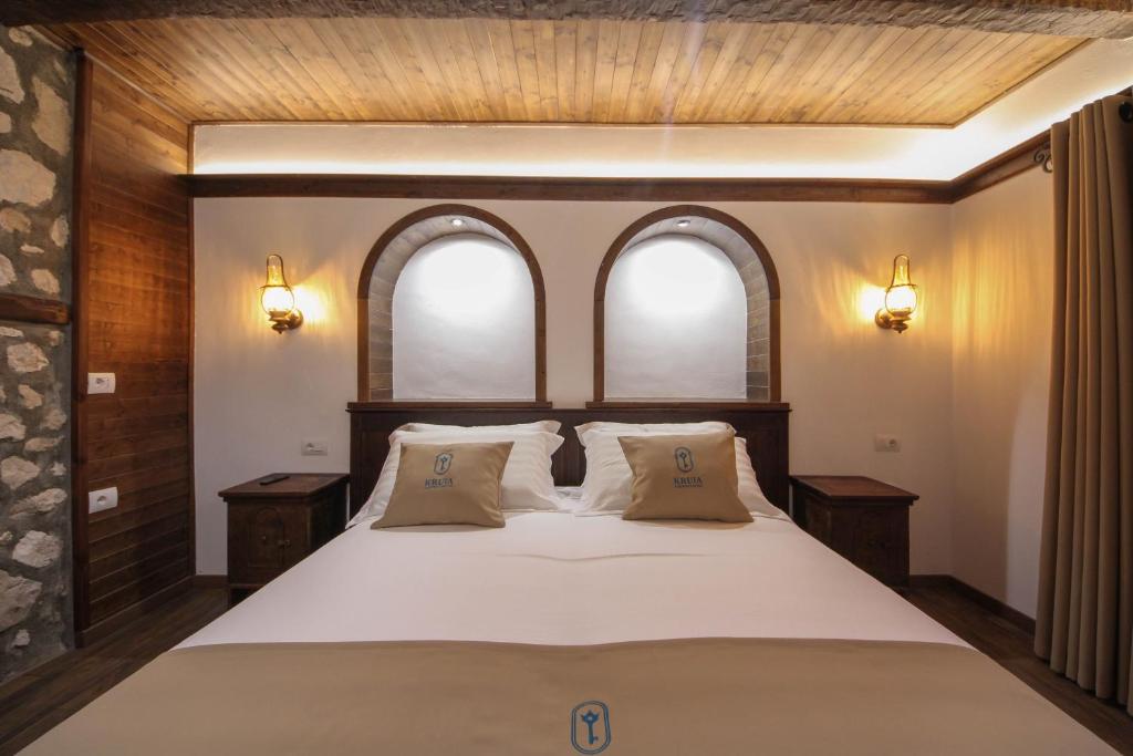 1 Schlafzimmer mit einem großen Bett und 2 Fenstern in der Unterkunft Kruja Albergo Diffuso , Inside Kruja Castle in Kruja