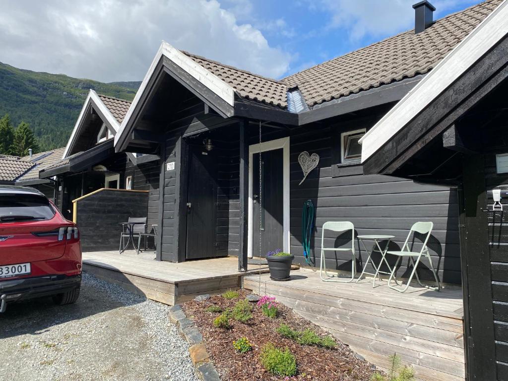 a black house with a wooden porch and a red car at Voss - Flott hytte i Bavallen in Skulestadmo