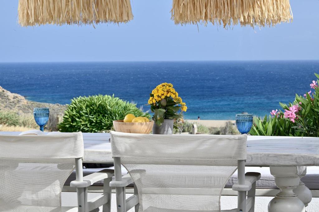 a table and chairs with the ocean in the background at VLIA MAR Myconian Residences in Kalafatis