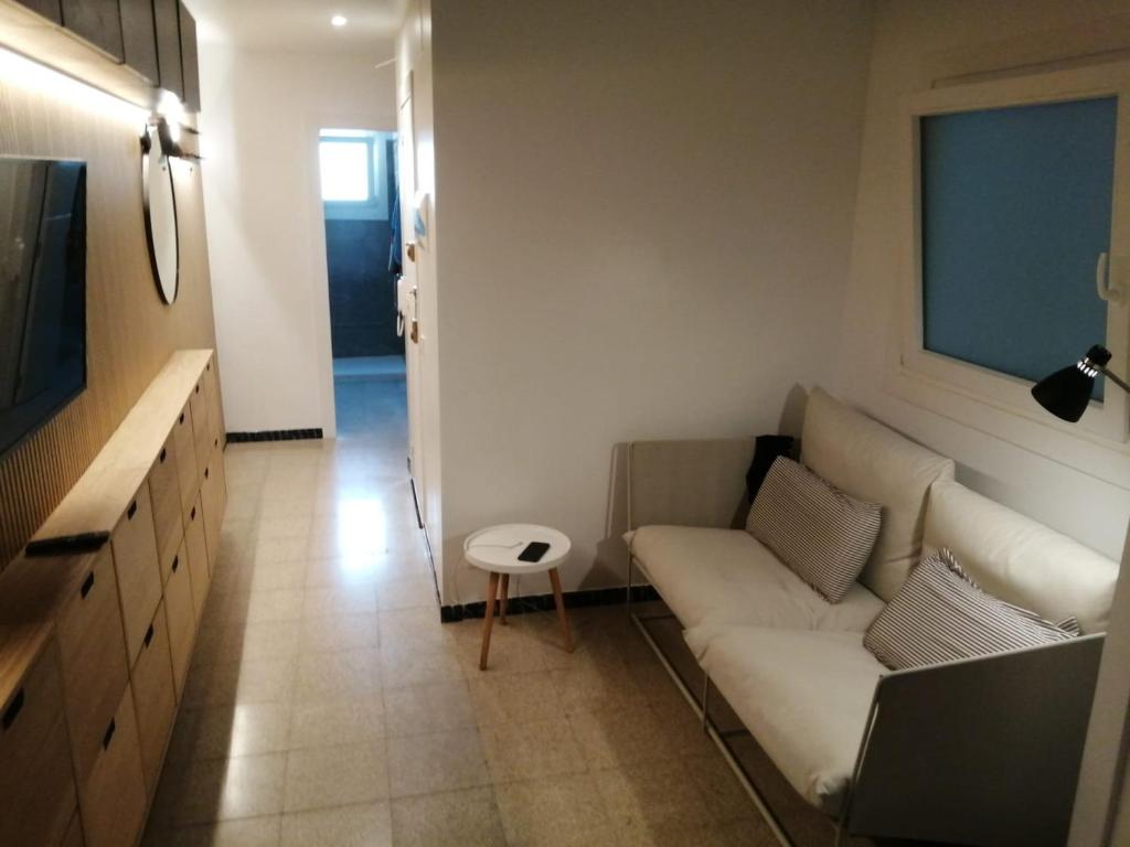 ein Wohnzimmer mit einem weißen Sofa und einem TV in der Unterkunft Newly renovated 2 bed apartment in Blanes old town 50m from the beach! in Blanes