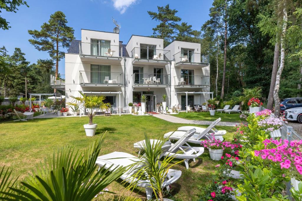 - un grand bâtiment blanc avec des chaises et des fleurs dans l'établissement Majestique, à Pobierowo