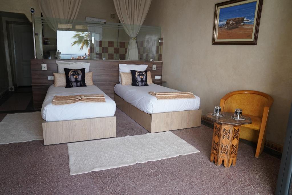 a room with two beds and a table with a tableasonable at Riad Ras Lafaa in Safi