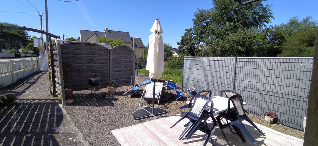 une terrasse avec des chaises, un parasol et une clôture dans l'établissement La Doris, à Saint-Pair-sur-Mer