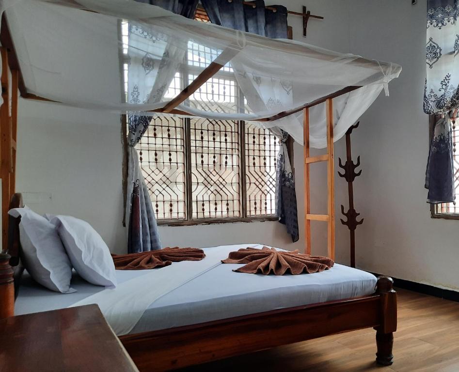 a bedroom with a canopy bed and a window at Kajificheni House in Nungwi