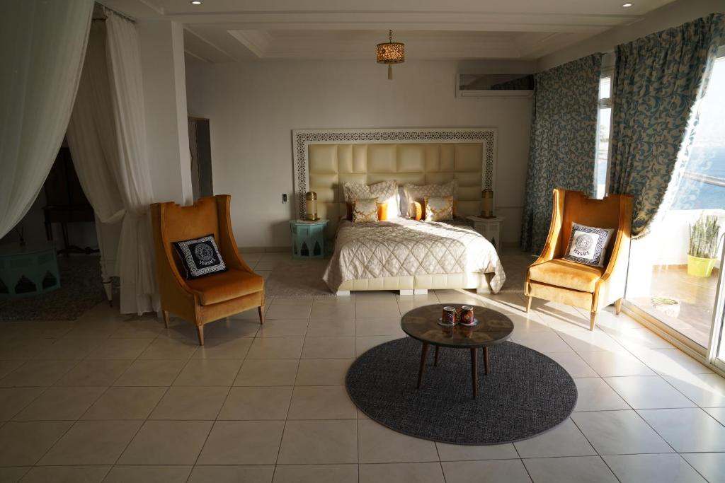 a bedroom with a bed and two chairs and a table at Riad Ras Lafaa in Safi