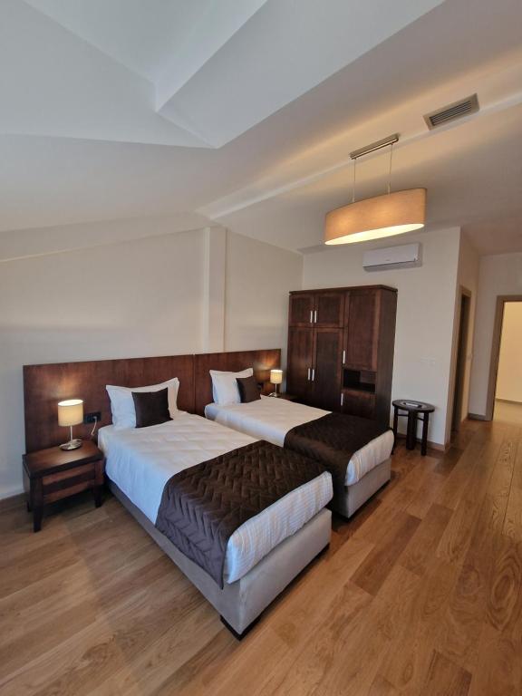 a hotel room with two beds and two tables at Vinarija Aleksandrović Rooms in Topola