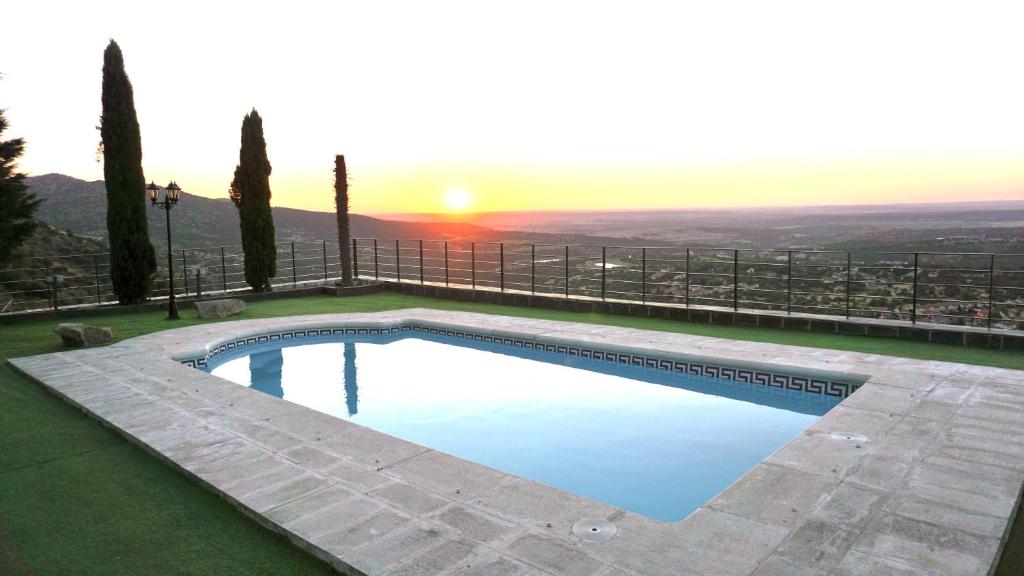 uma piscina com o pôr-do-sol ao fundo em VILLA LUXURY LOS ANGELES em El Espinar