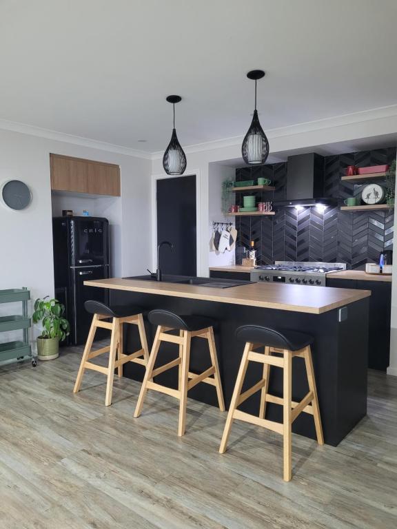 a kitchen with a large black island and stools at New apartment 3 min to Sovereign Hill & Wildlife Park in Ballarat