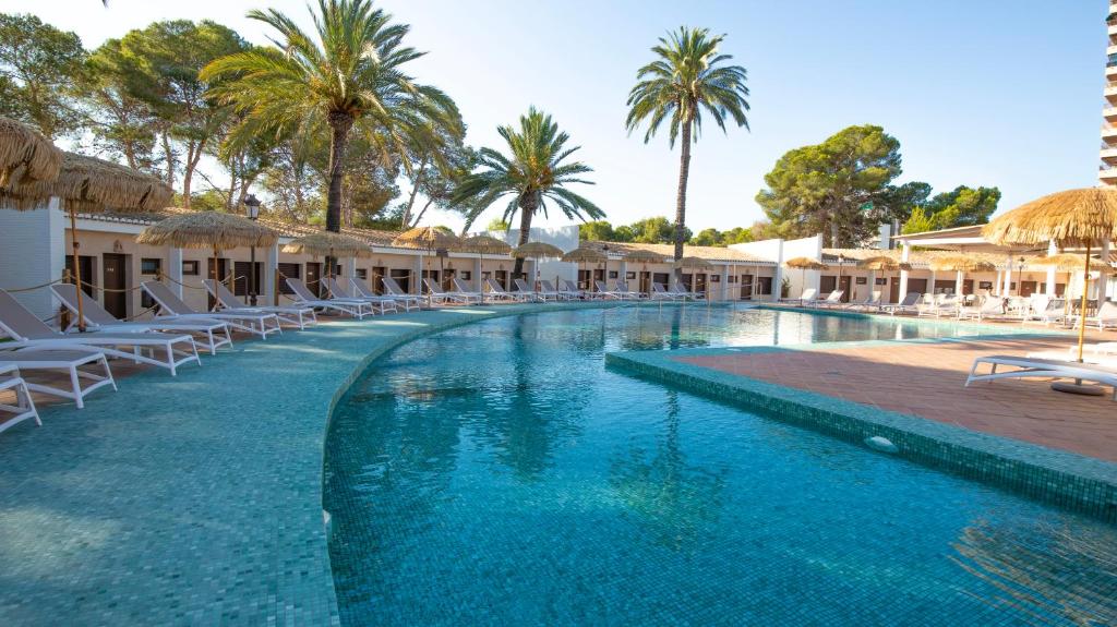 a pool at a resort with chairs and palm trees at Hotel Montepiedra 4''''sup in Playas de Orihuela