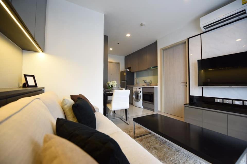 Super Luxury Condo في بانكوك: غرفة معيشة مع أريكة بيضاء ومطبخ