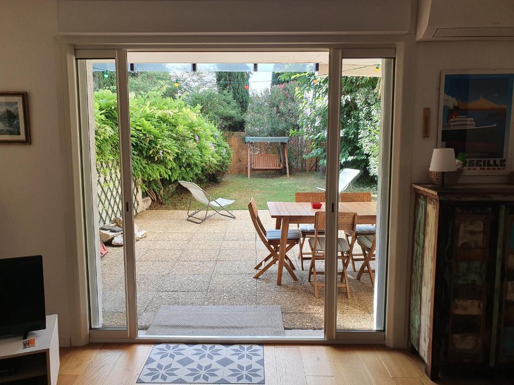Une porte ouverte s'ouvre sur une terrasse avec une table et des chaises. dans l'établissement La Balancelle, à Marseille