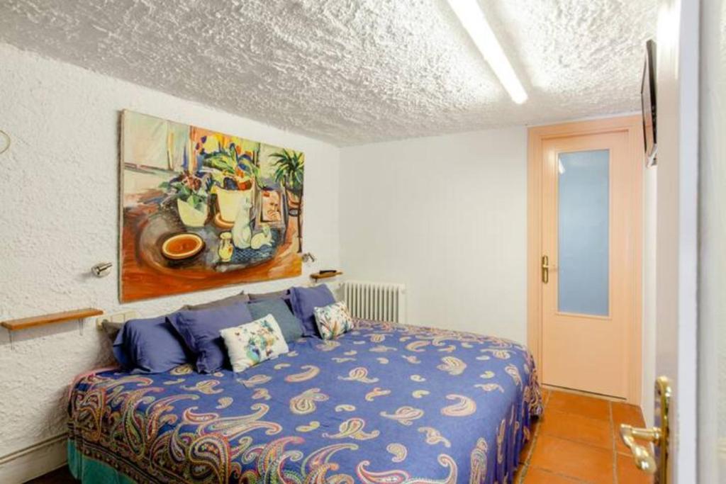 1 dormitorio con 1 cama con una pintura en la pared en MASIA CAN SUNYER AGROTURISMO en La Garriga