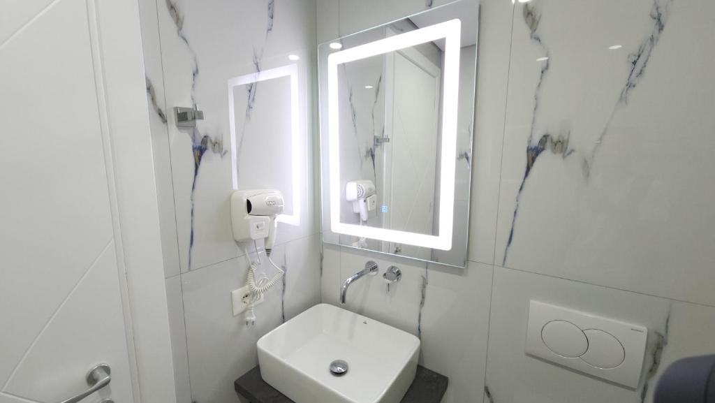 a white bathroom with a sink and a mirror at Noa Boutique Hotel in Ksamil