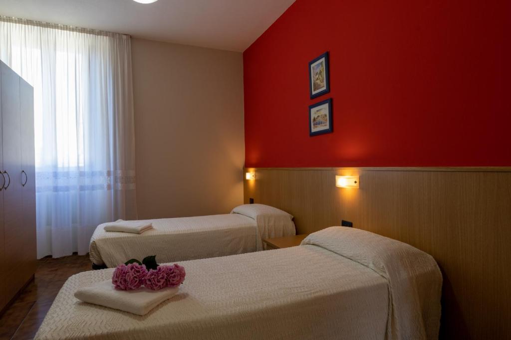 Habitación con 2 camas y pared roja. en Albergo San Michele, en Tirano