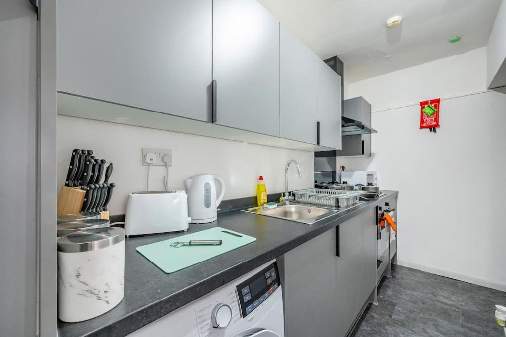 a kitchen with white cabinets and a sink at *F6GH For your most relaxed & cosy stay + FREE PARKING & WiFi in Bramley