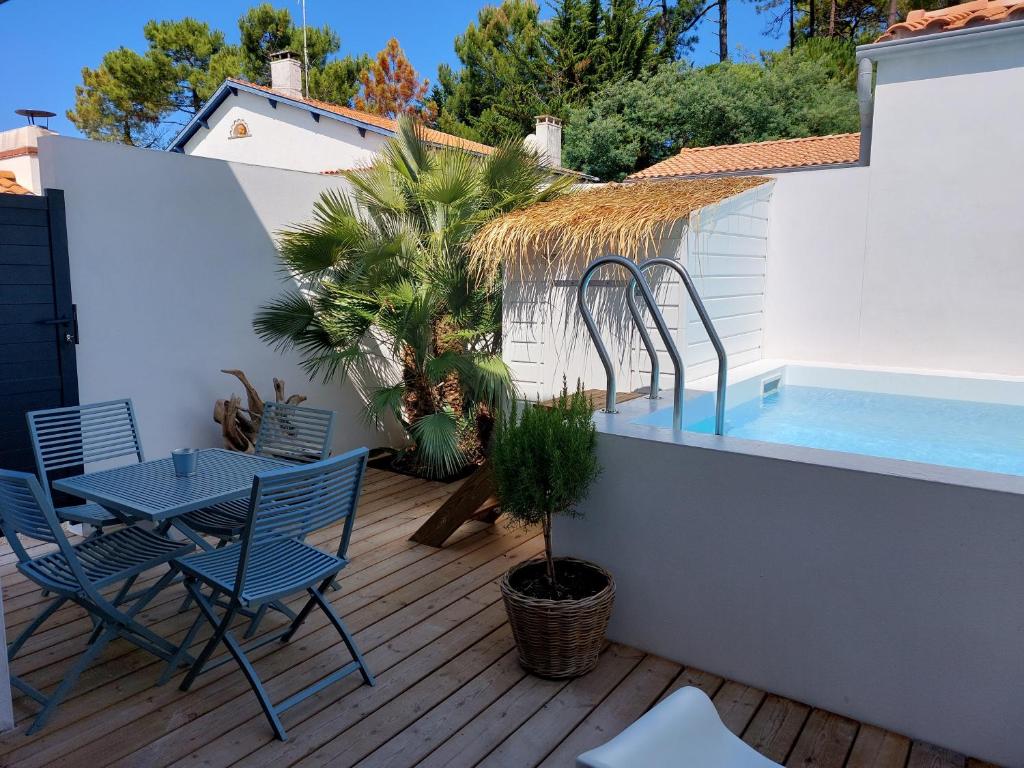 un patio avec une table et des chaises et une piscine dans l'établissement LOCATIONS NOS ILES, à Saint-Jean-de-Monts