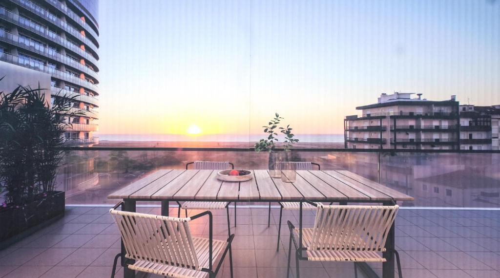 a table and chairs on a balcony with the sunset at OASIS in Buarcos