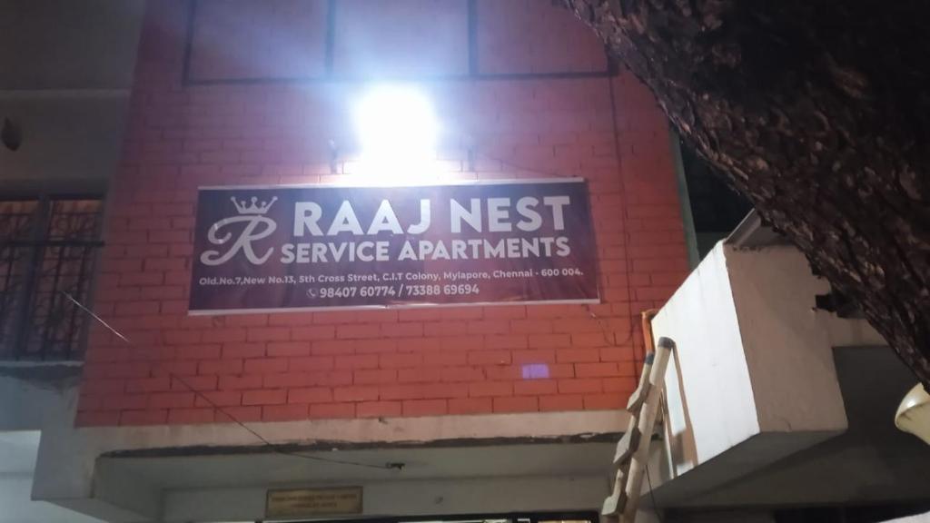 una señal en el lateral de un edificio de ladrillo en RAAJNEST SERVICE APARTMENTS en Chennai