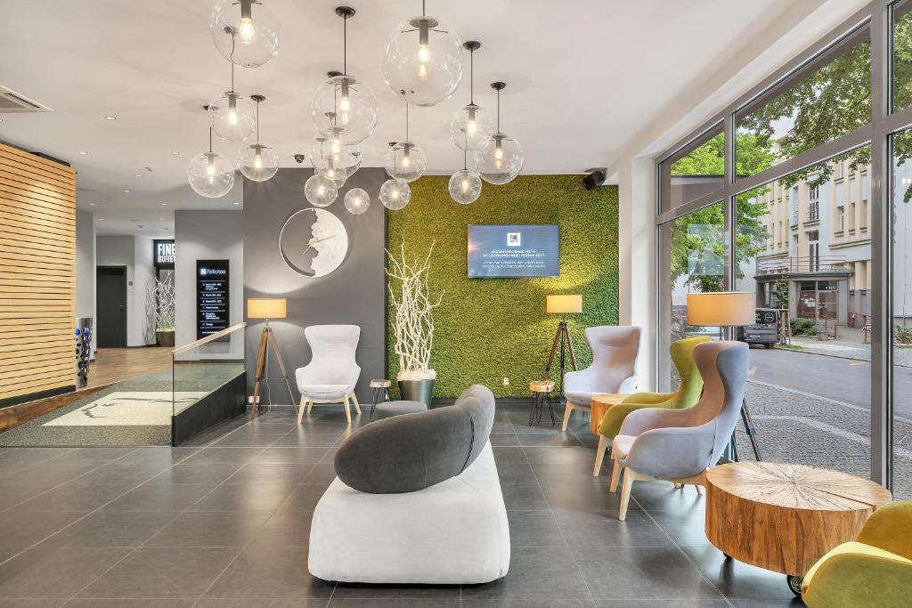 a lobby with chairs and tables and a wall of windows at Spa Hotel Felicitas in Poděbrady