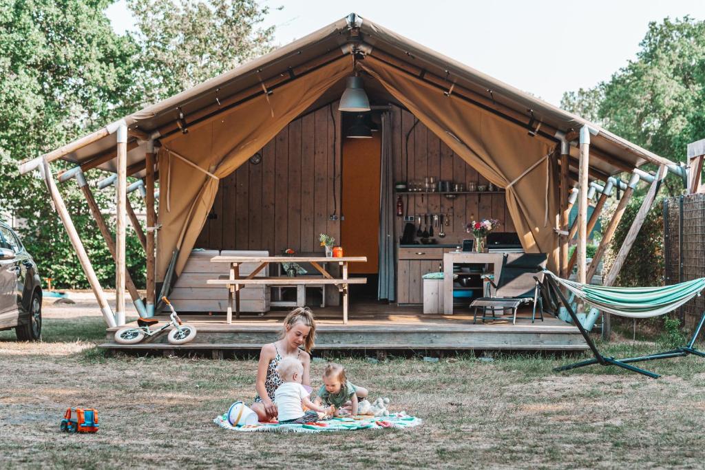 eine Frau und zwei Kinder, die vor einem Zelt sitzen in der Unterkunft Glamping Holten luxe safaritent 2 in Holten
