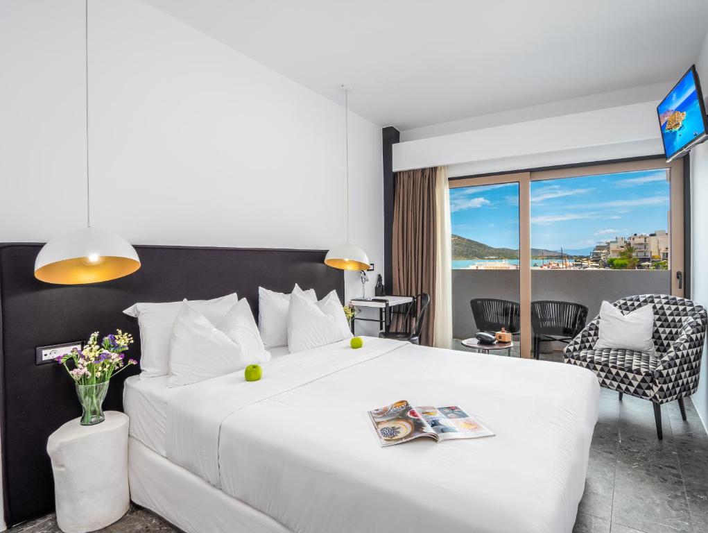 - une chambre avec un grand lit blanc et une vue dans l'établissement Kalypso Suites Hotel - Adults Only, à Elounda