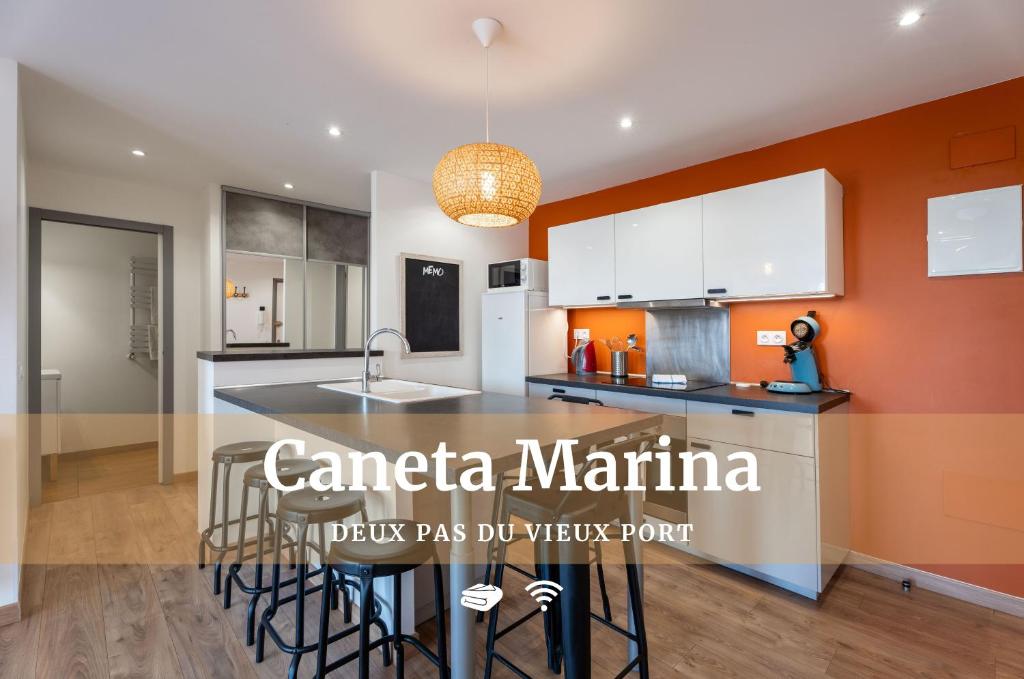 una cocina con paredes de color naranja y una isla de cocina con taburetes en Caneta Marina - Familial et Lumineux au Port de Caneta, Wi-Fi, en Hendaya