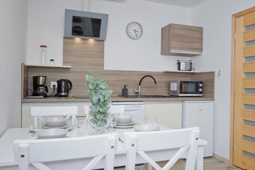 een keuken met een witte tafel en witte stoelen bij Lili Domki Letniskowe in Karwia