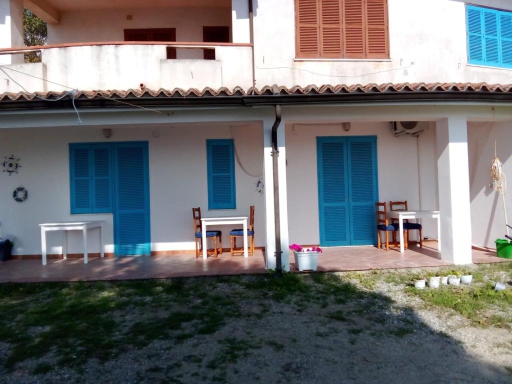 a house with blue doors and chairs on a patio at B&B Cala Del Borgo in Santa Maria