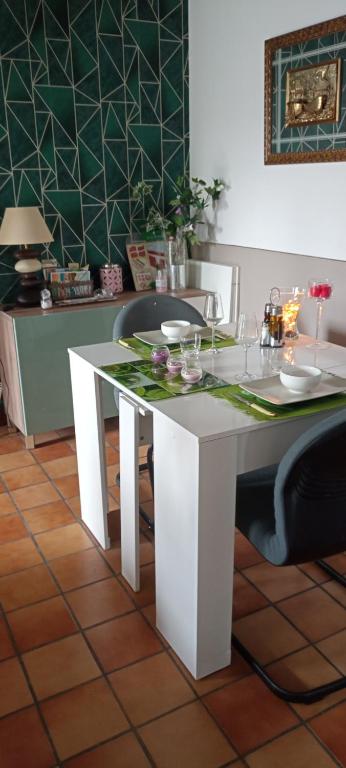 uma mesa de jantar branca com cadeiras e uma mesa com copos em logement entier 5 personnes em Irissarry