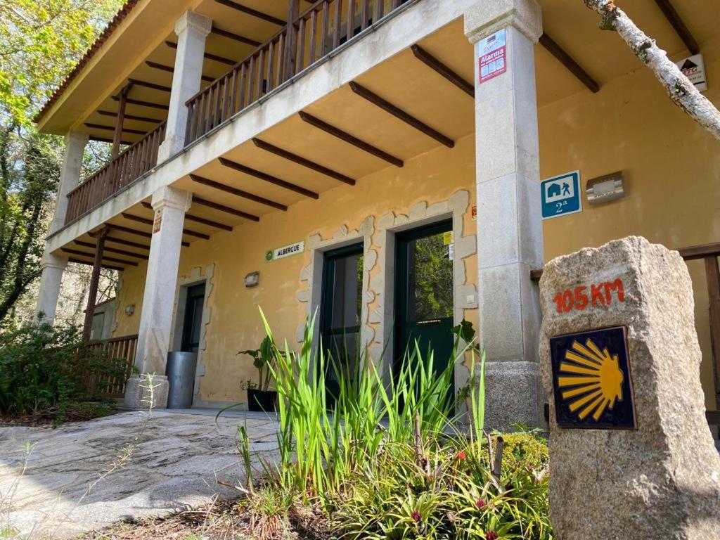 a building with a porch with a sign in front of it at Albergue O Beque in Moaña