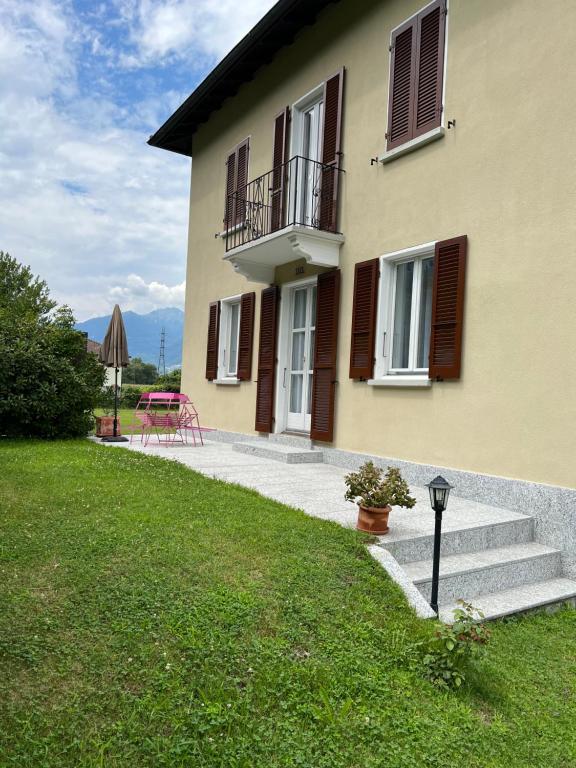 a house with a porch and stairs next to a yard at Casa Romana in Gambarogno