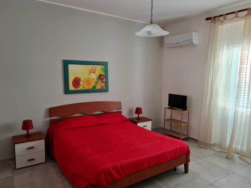 シラクーサにあるChiara Apartmentのベッドルーム(赤いベッド1台、テレビ付)