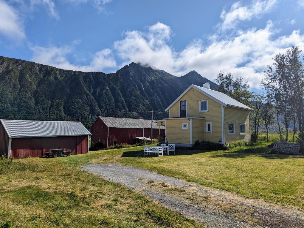 a house and barn with a mountain in the background at Sommarhus i Lofoten in Sand