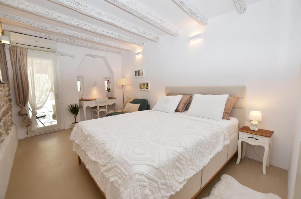 ロヴィニにあるApartment Al Pozzoの白いベッドルーム(大型ベッド1台、テーブル付)