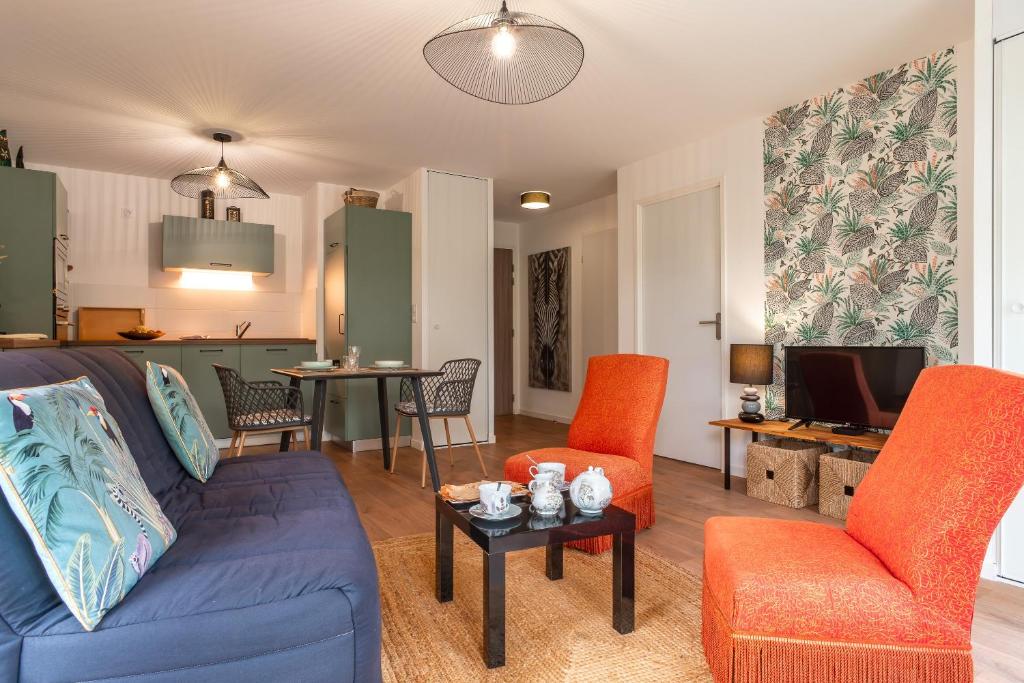 uma sala de estar com um sofá azul e cadeiras laranja em Îlots Dido - Appt proche de la mer em Concarneau