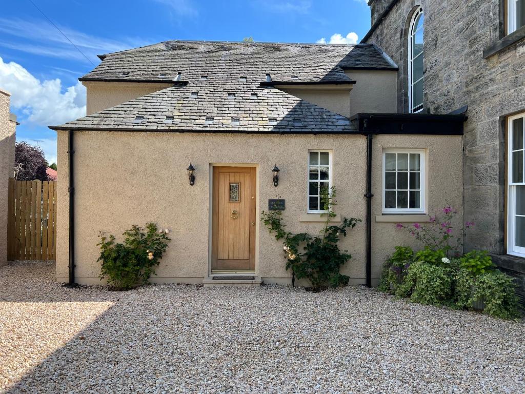 Loanhead的住宿－Quaint self contained cottage near Edinburgh.，砂石车道上一扇棕色门的房子