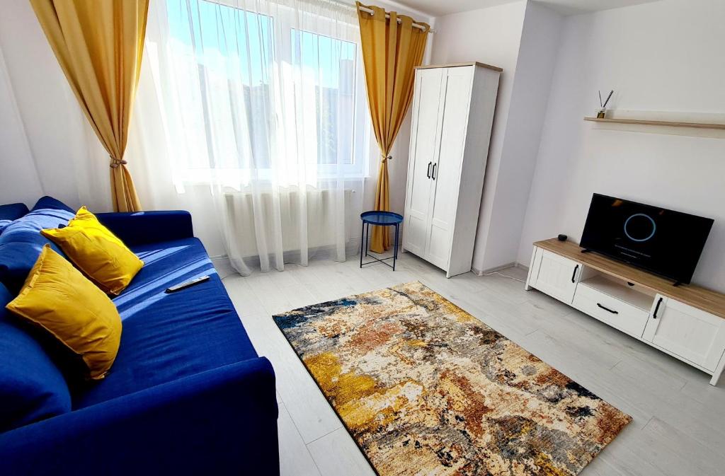 a living room with a blue couch and a television at Belle Apartments - Central in Piteşti