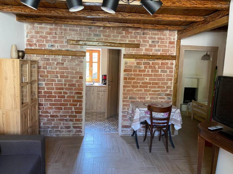a living room with a brick wall and a table and chairs at Aristos Cottage in Káto Lekhónia