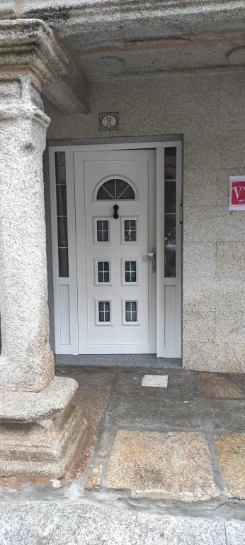 una puerta blanca en un edificio con un pilar de piedra en Las 4 columnas (MFA), en Muxía